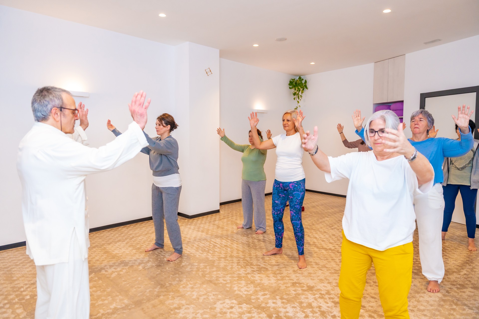 Qi gong teacher leading a class full of mature women